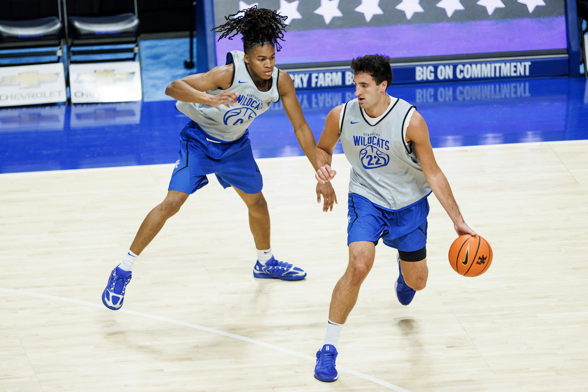A picture of Milan Momcilovic dribbling a basketball and being guarded by Zyon Hawthorne